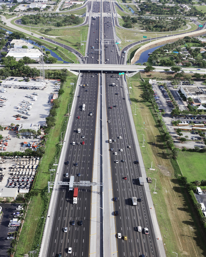 Aerial view of a highway with a level crossing to the bottom